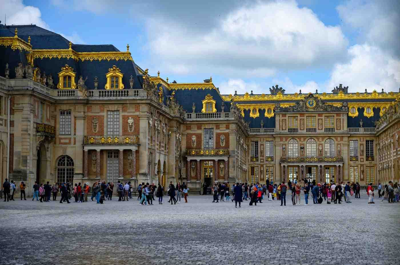 Golden ornate gates at the entrance of the Palace of Versailles.